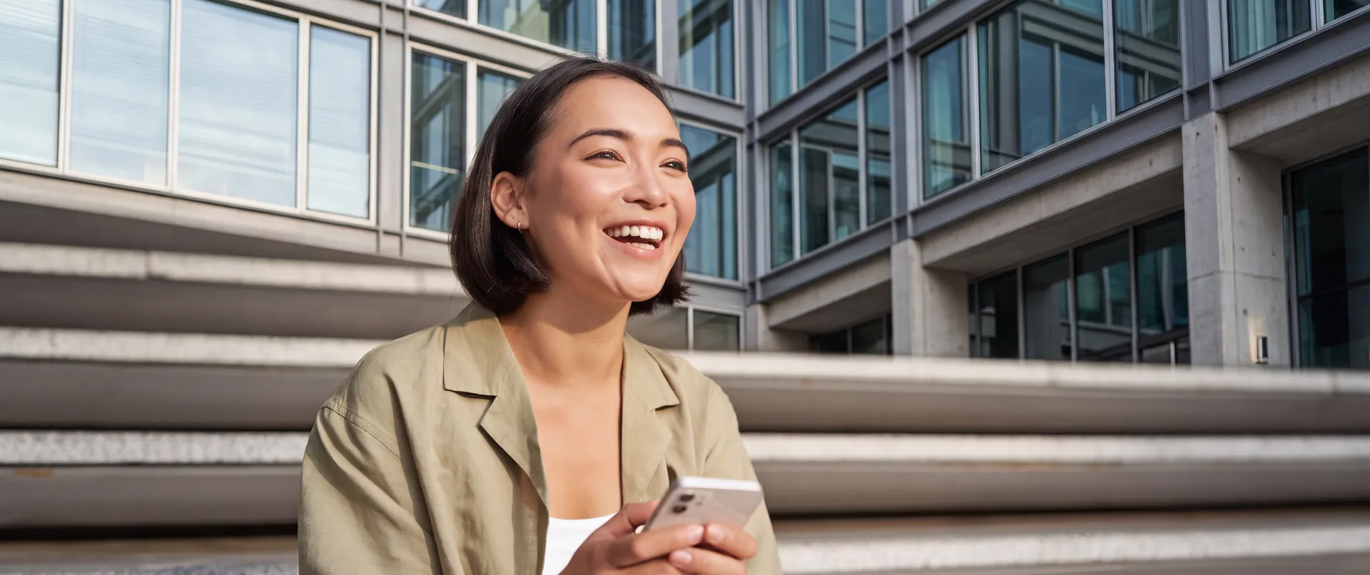 Mulher sorrindo ao ar livre, segurando o celular